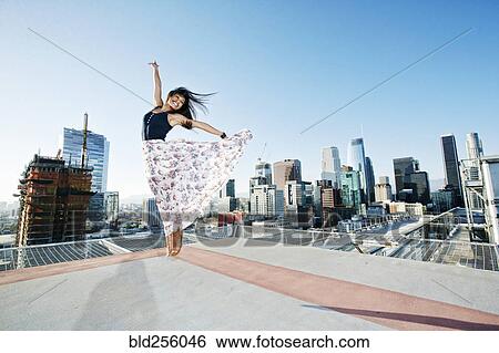 Asian woman jumping on urban rooftop View Large Photo Image Stock Photograph - Asian woman jumping on urban rooftop. Fotosearch