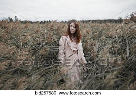 Stock Image - Asian woman standing in field. Fotosearch