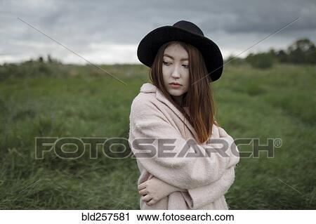 Stock Image - Asian woman standing in field. Fotosearch