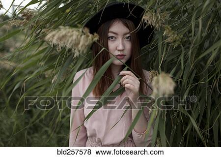 Asian woman standing in foliage View Large Photo Image Stock Photo - Asian woman standing in foliage. Fotosearch