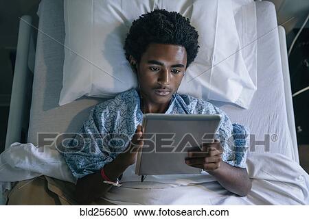Black boy in hospital bed listening to digital tablet View Large Photo Image Stock Image - Black boy in hospital bed listening to digital tablet. Fotosearch