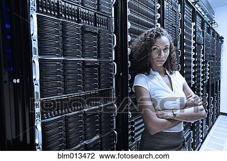 Stock Image - Black businesswoman standing in server room. Fotosearch