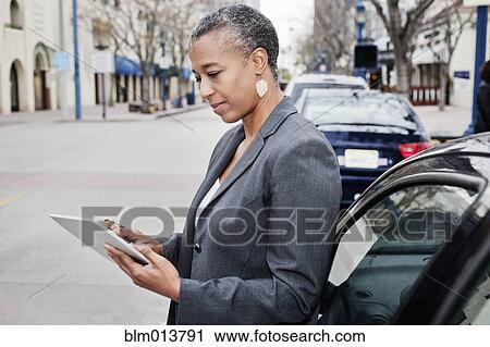 Stock Image - Black businesswoman using digital tablet outdoors. Fotosearch
