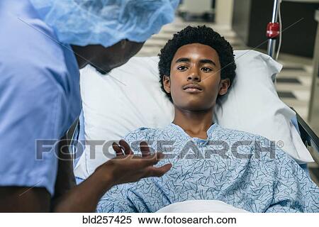 Stock Photography - Black doctor talking to boy in hospital bed. Fotosearch