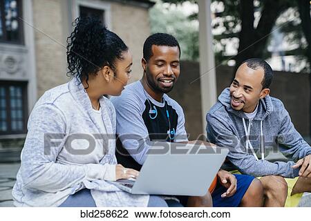 Black friends sitting outdoors using laptop View Large Photo Image Stock Image - Black friends sitting outdoors using laptop. Fotosearch