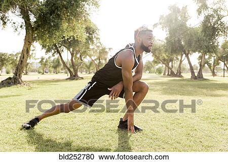 Black man crouching in park stretching legs View Large Photo Image Stock Image - Black man crouching in park stretching legs. Fotosearch