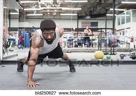 Stock Photo - Black man doing push-up in gymnasium. Fotosearch