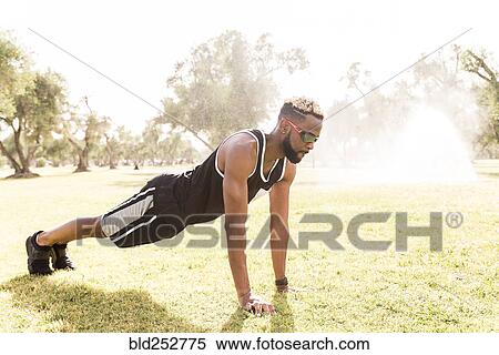Stock Photography - Black man doing push-ups in park. Fotosearch