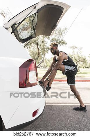 Black man leaning on car hatchback stretching leg View Large Photo Image Stock Photo - Black man leaning on car hatchback stretching leg. Fotosearch