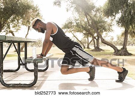 Black man leaning on picnic table in park stretching legs View Large Photo Image Stock Image - Black man leaning on picnic table in park stretching legs. Fotosearch