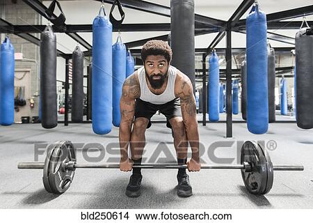 Picture - Black man lifting barbell in gymnasium. Fotosearch
