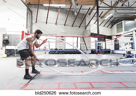 Black man lifting heavy ropes in gymnasium View Large Photo Image Stock Photograph - Black man lifting heavy ropes in gymnasium. Fotosearch
