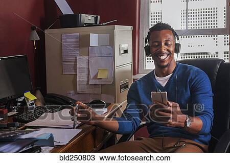 Black man listening to cell phone with headphones View Large Photo Image Stock Image - Black man listening to cell phone with headphones. Fotosearch