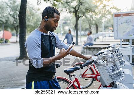 Black man paying for bicycle rental with cell phone View Large Photo Image Stock Image - Black man paying for bicycle rental with cell phone. Fotosearch