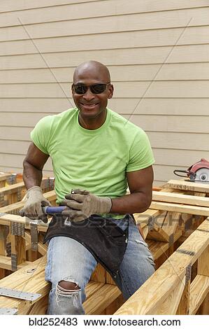 Black man posing with hammer at construction site View Large Photo Image Stock Image - Black man posing with hammer at construction site. Fotosearch