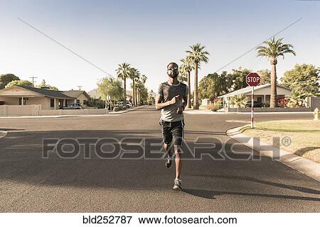 Stock Photo - Black man running on street in neighborhood. Fotosearch