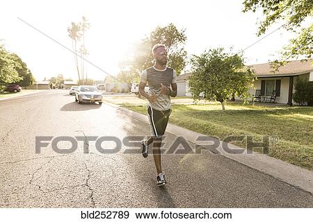 Stock Photo - Black man running on street in neighborhood. Fotosearch