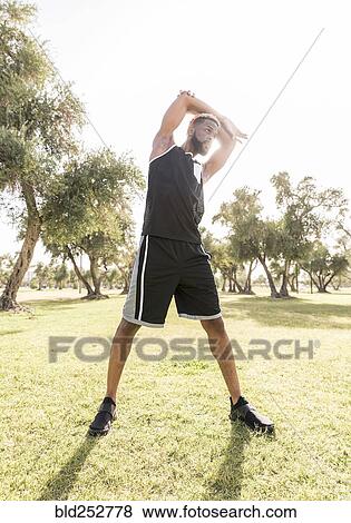 Stock Photo - Black man stretching arms in park. Fotosearch