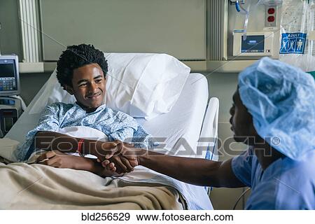 Stock Photo - Black nurse shaking hands with boy in hospital bed. Fotosearch