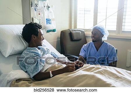 Stock Photo - Black nurse talking to boy in hospital bed. Fotosearch