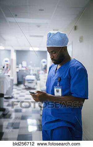 Black nurse texting on cell phone in hospital View Large Photo Image Stock Image - Black nurse texting on cell phone in hospital. Fotosearch