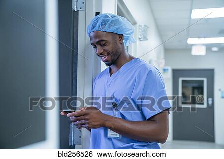 Stock Photograph - Black nurse texting on cell phone. Fotosearch