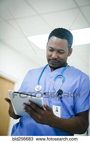 Black nurse using digital tablet in hospital View Large Photo Image Stock Image - Black nurse using digital tablet in hospital. Fotosearch