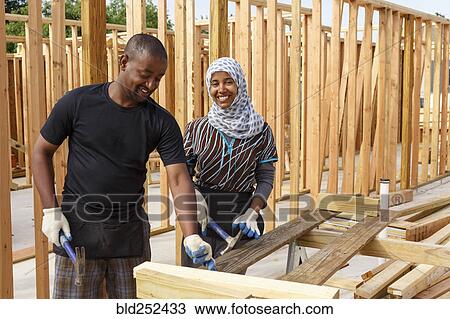 Stock Image - Black volunteers building house. Fotosearch
