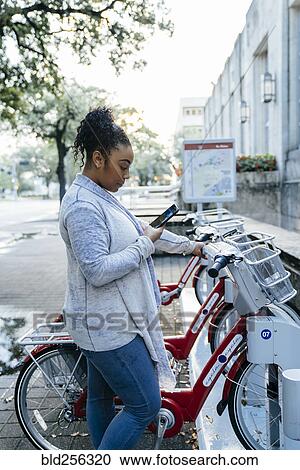Black woman paying for bicycle rental with cell phone View Large Photo Image Stock Image - Black woman paying for bicycle rental with cell phone. Fotosearch