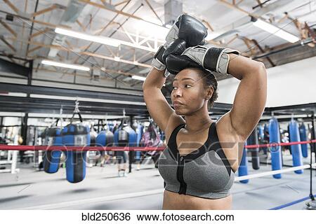 Stock Photograph - Black woman resting with arms raised in boxing ring. Fotosearch