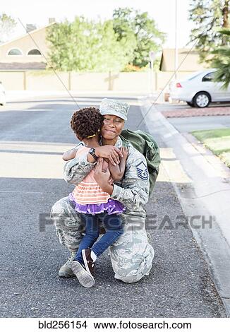Picture - Black woman soldier greeting daughter in street. Fotosearch