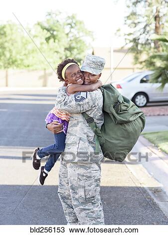 Stock Image - Black woman soldier hugging daughter in street. Fotosearch