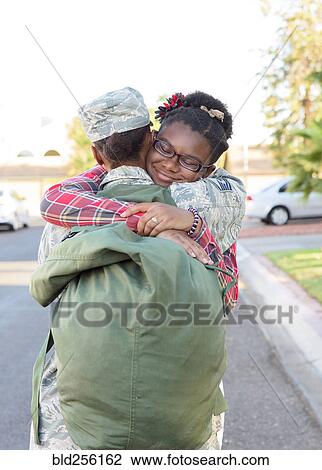 Stock Image - Black woman soldier hugging daughter in street. Fotosearch