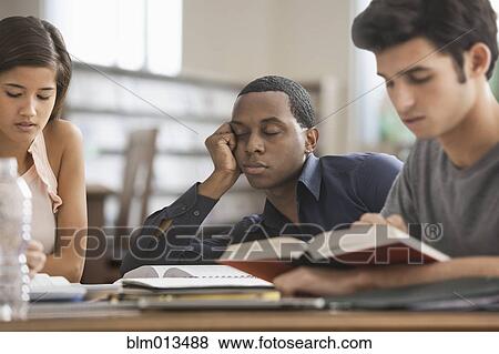 Stock Photo - Bored student studying with friends. Fotosearch
