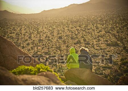 Boys sitting on rock admiring desert landscape View Large Photo Image Stock Image - Boys sitting on rock admiring desert landscape. Fotosearch