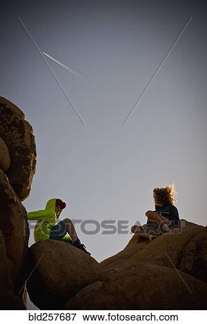 Boys sitting on rocks under blue sky View Large Photo Image Stock Photo - Boys sitting on rocks under blue sky. Fotosearch