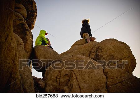 Boys sitting on rocks under blue sky View Large Photo Image Stock Photo - Boys sitting on rocks under blue sky. Fotosearch