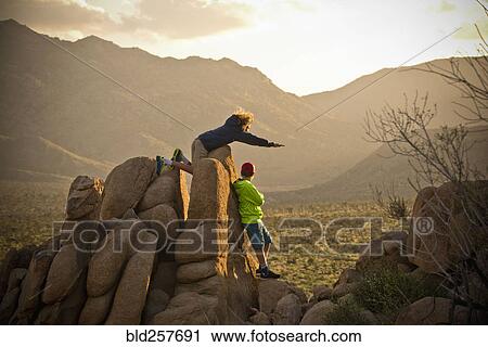 Stock Image - Boys standing on rocks admiring desert landscape. Fotosearch
