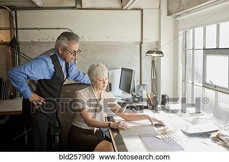 Stock Photo - Business people examining parts in office. Fotosearch