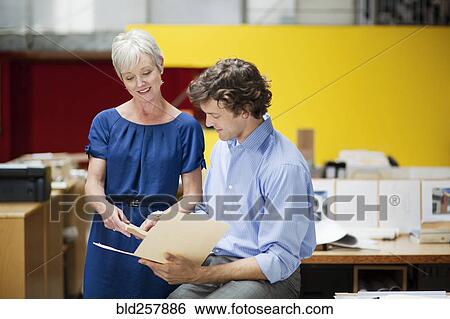Stock Photograph - Business people reading file folder in office. Fotosearch