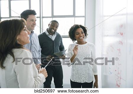 Stock Photo - Business people reading whiteboard in meeting. Fotosearch