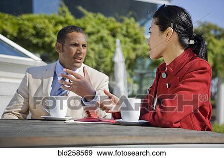 Stock Photo - Business people talking and drinking coffee outdoors. Fotosearch