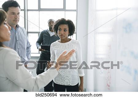 Business people talking near whiteboard in meeting View Large Photo Image Picture - Business people talking near whiteboard in meeting. Fotosearch