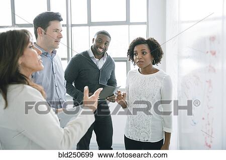 Business people talking near whiteboard in meeting View Large Photo Image Stock Photo - Business people talking near whiteboard in meeting. Fotosearch