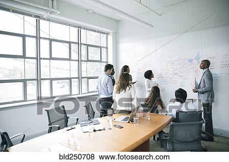 Stock Photo - Business people talking near whiteboard in meeting. Fotosearch