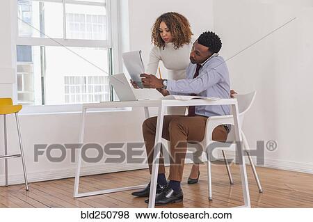 Stock Photo - Business people talking on cell phone and reading notepad. Fotosearch