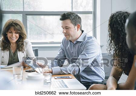 Stock Image - Business people using digital tablet in meeting. Fotosearch