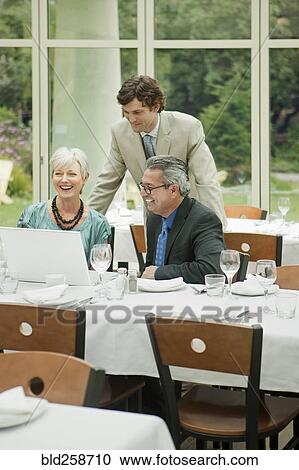 Business people using laptop at restaurant View Large Photo Image Stock Image - Business people using laptop at restaurant. Fotosearch
