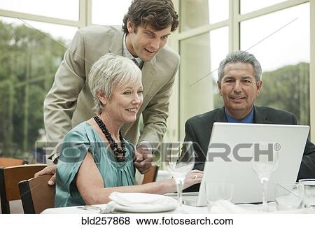 Business people using laptop at table in restaurant View Large Photo Image Stock Photo - Business people using laptop at table in restaurant. Fotosearch
