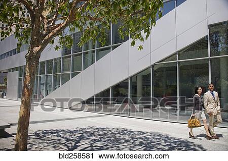 Stock Image - Business people walking near building. Fotosearch